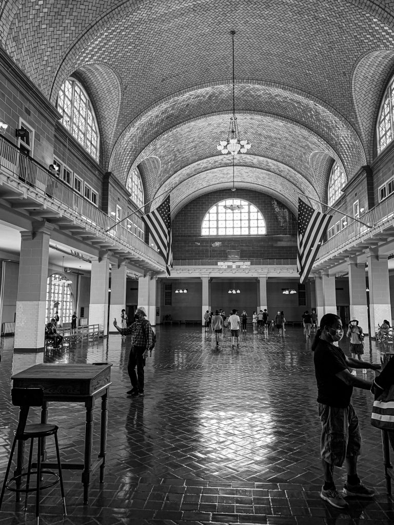 Inside the great hall of Ellis Island, where millions of immigrants first set foot in America, history echoes through the vaulted ceilings and polished floors. The symmetry of the arches, the quiet presence of the flags, and the scattered figures in motion capture both the grandeur and the intimacy of this space. A timeless moment where architecture, memory, and humanity converge.